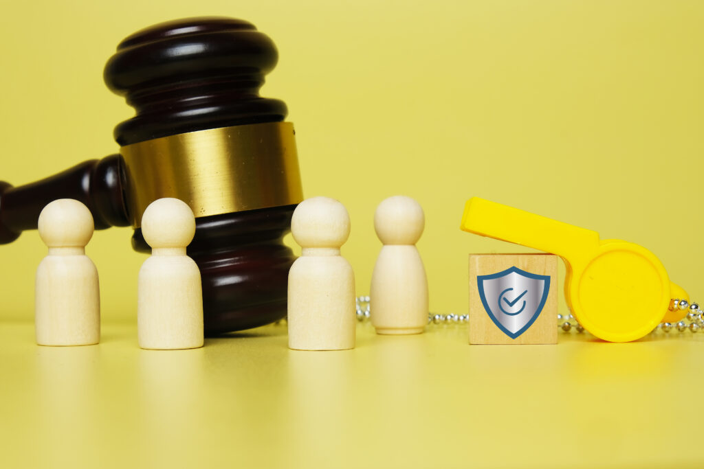 Yellow whistle resting on a block with a shield on it and a gavel to the left.