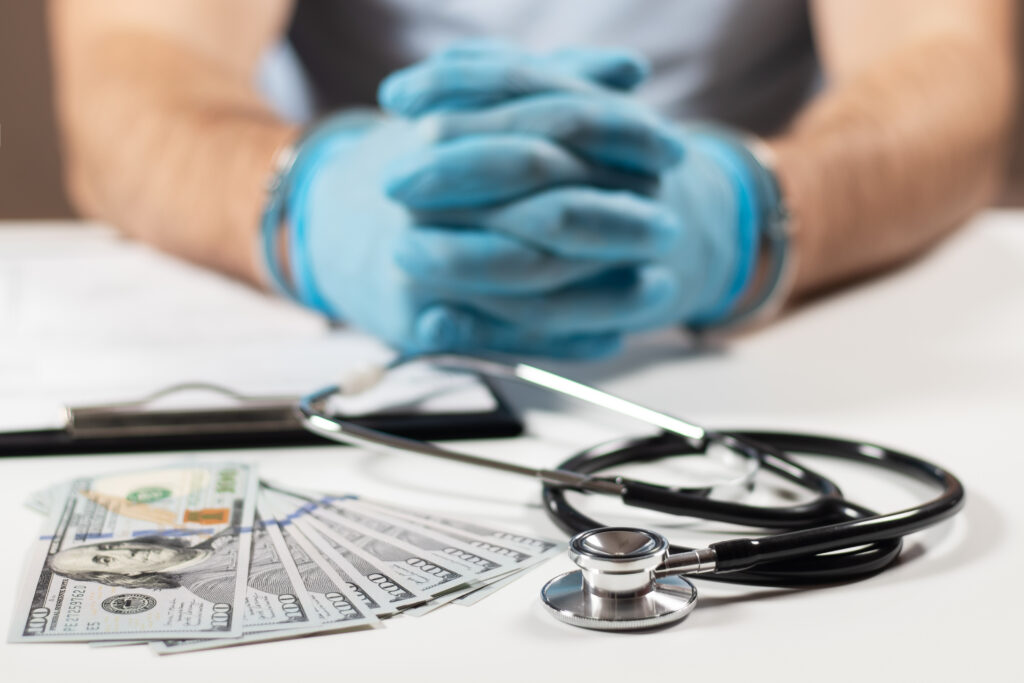 Doctor in handcuffs with money on table. Healthcare fraud concept.