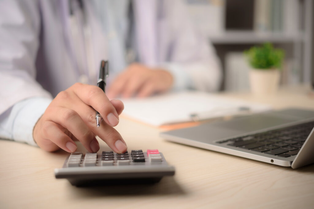 Doctor using calculator for billing. Healthcare fraud concept.