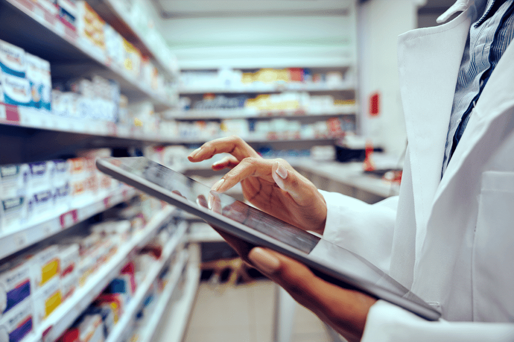 A pharmacist using a tablet while in the back of the shop. Healthcare fraud concept.